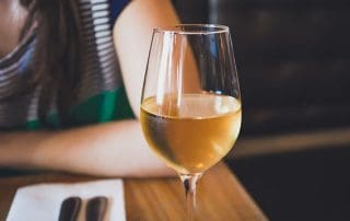 a glass of wine next to a woman