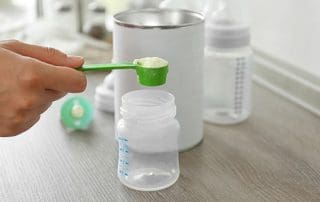 Preparing baby formula on wooden table closeup