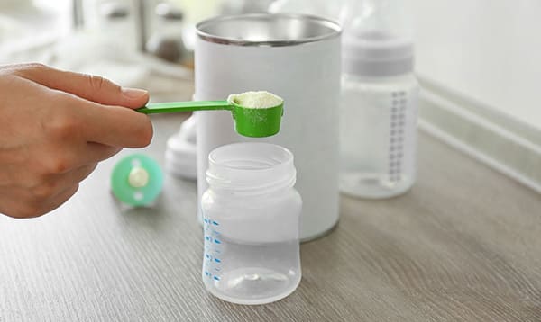 Preparing baby formula on wooden table closeup