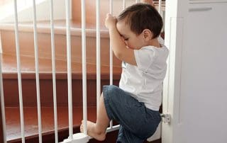 boy climbing over child safety gate, babyproofed home