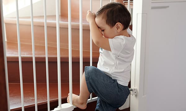 boy climbing over child safety gate, babyproofed home