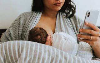 what it really takes to breastfeed a baby- mom with phone while breastfeeding