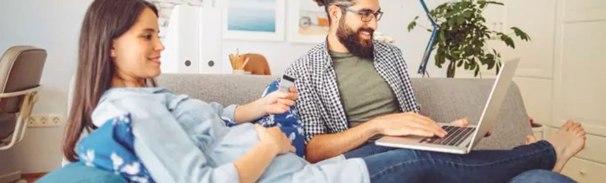 Pregnant couple on sofa with computer watching 4 hour quick childbirth class