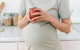 pregnant woman eating apple- How to Reduce the Risk of Preeclampsia