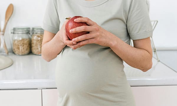 pregnant woman eating apple- How to Reduce the Risk of Preeclampsia