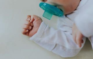 premature baby sleeping in a crib with a pacifier