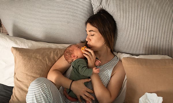 woman holding baby while resting during her sitting month