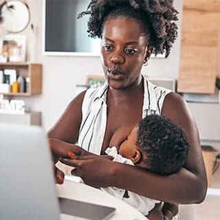 woman-nursing-at-laptop New mother breastfeeding her baby while working on laptop