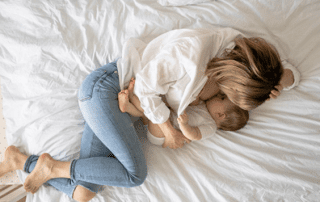 Adult lying on a bed while breastfeeding a baby, highlighting bed sharing and co-sleeping.