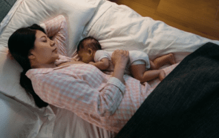 Mother sleeping next to baby after breastfeeding.