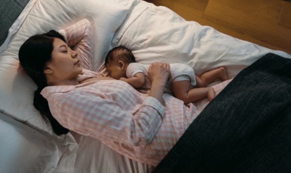 Mother sleeping next to baby after breastfeeding.