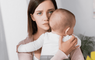 Woman holding baby highlighting the emotions and challenges of breastfeeding.