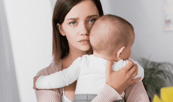 Woman holding baby highlighting the emotions and challenges of breastfeeding.