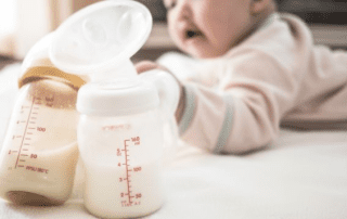 Infant with two baby bottles filled with milk, one with a breast pump attached, used for supplementing breastfeeding.