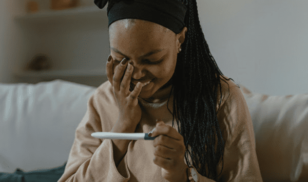 Person holding a pregnancy test, relevant to prenatal care in the first trimester.